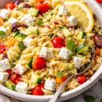 Colorful Greek Orzo Salad with feta, tomatoes, cucumbers, and olives served in a bowl.